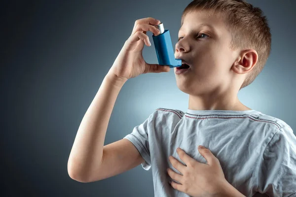 Retrato de un niño usando un inhalador de asma para tratar enfermedades inflamatorias, falta de aliento. El concepto de tratamiento para la tos, alergias, enfermedades del tracto respiratorio . — Foto de Stock