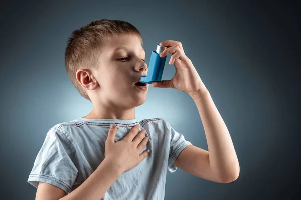 Retrato de um menino usando um inalador de asma para tratar doenças inflamatórias, falta de ar. O conceito de tratamento para a tosse, alergias, doença do trato respiratório . — Fotografia de Stock