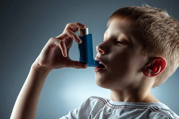 Retrato de um menino usando um inalador de asma para tratar doenças inflamatórias, falta de ar. O conceito de tratamento para a tosse, alergias, doença do trato respiratório . — Fotografia de Stock