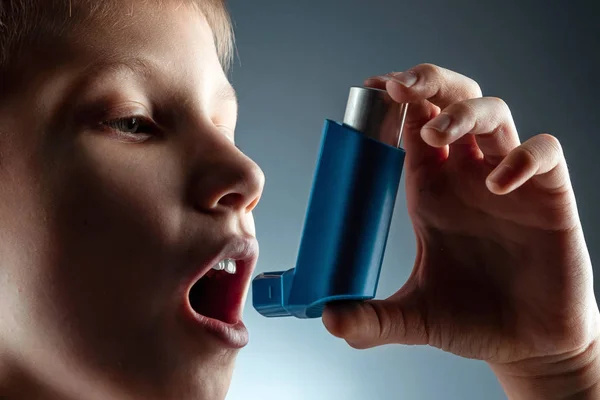 Portrait of a boy using an asthma inhaler to treat inflammatory diseases, shortness of breath. The concept of treatment for cough, allergies, respiratory tract disease. — Stock Photo, Image