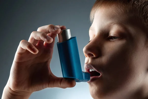 Retrato de un niño usando un inhalador de asma para tratar enfermedades inflamatorias, falta de aliento. El concepto de tratamiento para la tos, alergias, enfermedades del tracto respiratorio . — Foto de Stock