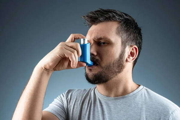 Ritratto di un uomo con un inalatore d'asma in mano, un attacco asmatico. Il concetto di trattamento di asma bronchiale, tosse, allergie, dispnea . — Foto Stock