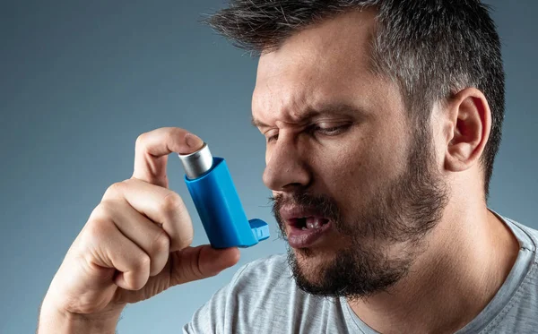 Portret mężczyzny z inhalatorem astmy w rękach, atak astmy. Koncepcja leczenia astmy oskrzelowej, kaszlu, alergii, duszności. — Zdjęcie stockowe