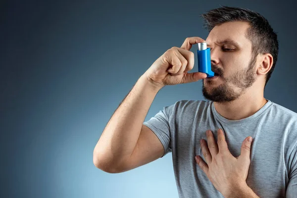 Portré egy férfiról asztmás inhalátorral a kezében, asztmás roham. A fogalom kezelésére bronchialis asztma, köhögés, allergia, dyspnoe. — Stock Fotó