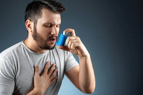 Ritratto di un uomo con un inalatore d'asma in mano, un attacco asmatico. Il concetto di trattamento di asma bronchiale, tosse, allergie, dispnea . — Foto Stock
