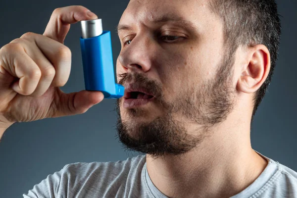 Portré egy férfiról asztmás inhalátorral a kezében, asztmás roham. A fogalom kezelésére bronchialis asztma, köhögés, allergia, dyspnoe. — Stock Fotó