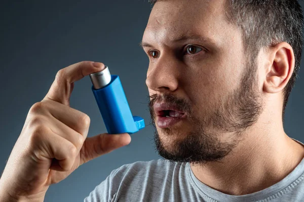 Porträt eines Mannes mit einem Asthma-Inhalator in den Händen, einem Asthmaanfall. das Konzept der Behandlung von Asthma bronchiale, Husten, Allergien, Atemnot. — Stockfoto