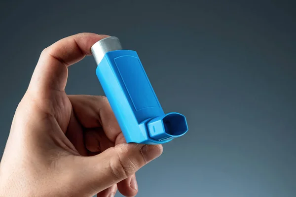 Close-up with an asthma inhaler in a male hand, asthmatic attack. The concept of treatment of bronchial asthma, cough, allergies, dyspnea. — 图库照片