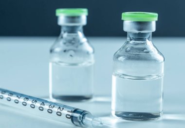 Vaccine in vial and syringe close-up on a white table gray background, medical concept, laboratory, subcutaneous injection vaccination, dose. Disease treatment immunization.