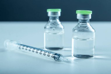 Vaccine in vial and syringe close-up on a white table gray background, medical concept, laboratory, subcutaneous injection vaccination, dose. Disease treatment immunization.