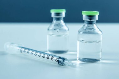 Vaccine in vial and syringe close-up on a white table gray background, medical concept, laboratory, subcutaneous injection vaccination, dose. Disease treatment immunization.