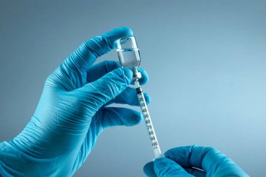Hand holding syringe Vaccine in vial closeup on gray background, medical concept vaccination subcutaneous injection, dose. Disease treatment immunization.