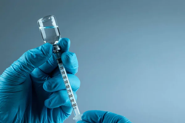Рука тримає шприц Вакцина в флаконі крупним планом на сірому фоні, медична концепція вакцинація підшкірної ін'єкції, доза. Лікування хвороби імунізація . — стокове фото