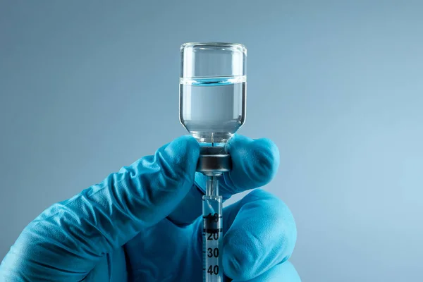 Hand holding syringe Vaccine in vial closeup on gray background, medical concept vaccination subcutaneous injection, dose. Disease treatment immunization. — Stockfoto