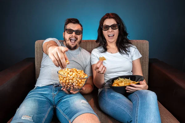 Un homme et une femme, une famille regardant un film ou une série en lunettes 3D, un fond bleu. Le concept de cinéma, films, émotions, surprise, loisirs, plateformes de streaming . — Photo