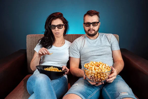 Un homme et une femme, une famille regardant un film ou une série en lunettes 3D, un fond bleu. Le concept de cinéma, films, émotions, surprise, loisirs, plateformes de streaming . — Photo
