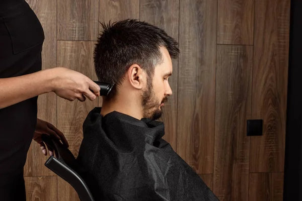 O mestre faz um corte de cabelo ao cliente com uma máquina elétrica, cortador, close-up. O processo de cortes de cabelo masculinos no cabeleireiro, barbearia. Cuidados com o corpo, estilo de vida, metrosexual . — Fotografia de Stock