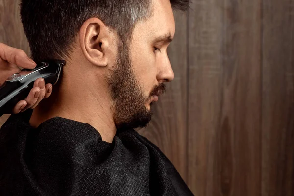 O mestre faz um corte de cabelo ao cliente com uma máquina elétrica, cortador, close-up. O processo de cortes de cabelo masculinos no cabeleireiro, barbearia. Cuidados com o corpo, estilo de vida, metrosexual . — Fotografia de Stock