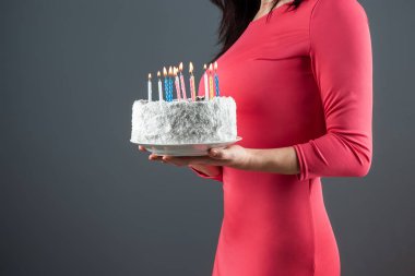 Pembe elbiseli bir kız elinde yanan mumlu bir pasta tutuyor, yakın plan. Doğum günü kutlaması yıldönümünüz kutlu olsun. Boşluğu kopyala.