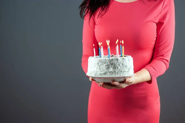 Una chica con un vestido rosa sostiene en sus manos un pastel con velas encendidas, de cerca. Feliz cumpleaños fiesta de felicitación aniversario. Copiar espacio . —  Fotos de Stock
