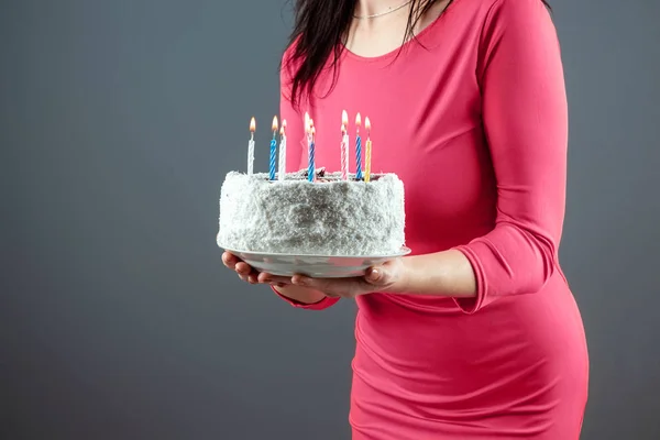 Una chica con un vestido rosa sostiene en sus manos un pastel con velas encendidas, de cerca. Feliz cumpleaños fiesta de felicitación aniversario. Copiar espacio . —  Fotos de Stock