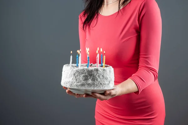 Een meisje in een roze jurk houdt in haar handen een taart met brandende kaarsen, close-up. Gelukkige verjaardag gefeliciteerd feest verjaardag. Kopieerruimte. — Stockfoto