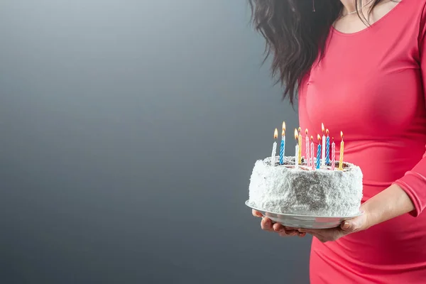 Дівчина в рожевій сукні тримає в руках торт з палаючими свічками, крупним планом. З днем народження привітання з святом вечірки. Копіювати простір . — стокове фото