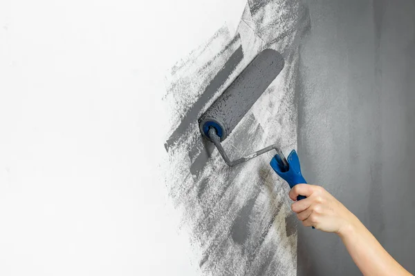 El primer plano femenino pinta la pared en gris. El concepto de reparación, cambio, diseño, loft interior — Foto de Stock