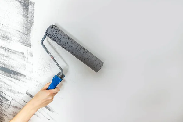 Il primo piano femminile dipinge una parete in grigio. Il concetto di riparazione, cambiamento, design, soppalco interno — Foto Stock