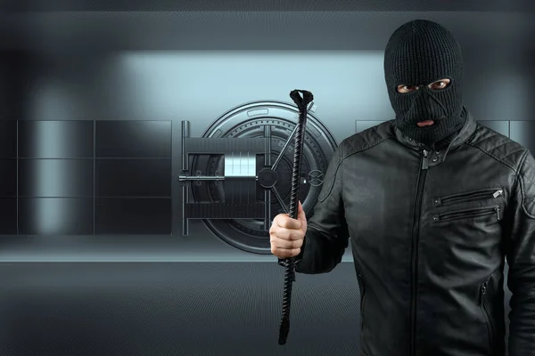 Masked burglar with crowbar in the background. Bank vault doors, large safe, bank robbery. The concept of deposit protection, protection of savings. Copy space, mixed medi