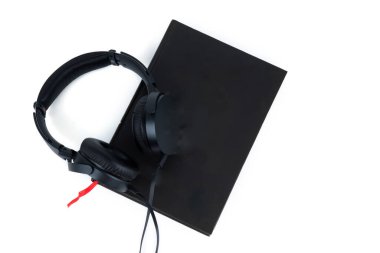 Siyah kulaklıklar ve beyaz arka planda izole edilmiş bir kitap. Audiobook konsepti kopyalama alanı