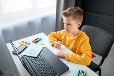 Uzaktan öğrenme, bir çocuk online ders sırasında dizüstü bilgisayara bakarken matematik öğreniyor. Çevrimiçi eğitim, ev eğitimi, teknoloji, karantina, kendini izole etme kavramı