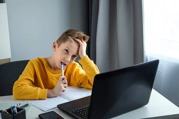 在远程学习中 一个男孩在网上学习数学的同时 还在看笔记本电脑的滴答声 网上教育 家庭教育 自我封闭的概念 — 图库照片
