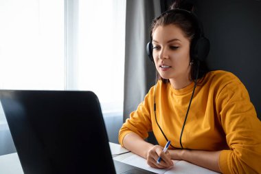 Evde dizüstü bilgisayar kullanan güzel bir kız, online iş konsepti, uzaktan kumanda. Webinar izlemek, sosyal ağlarda arkadaş aramak. Modern teknolojiler