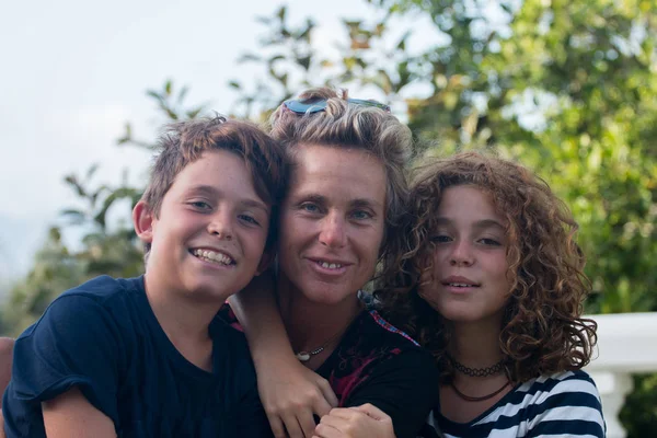 Onun iki çocuğu ile poz genç anne ve kız, evinin bahçesinde gülümseyen