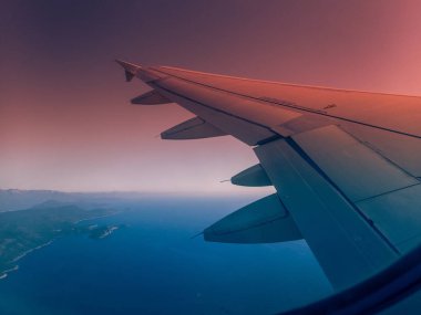 Gün doğumunda sahil şeridinde uçan uçağın kanadı.