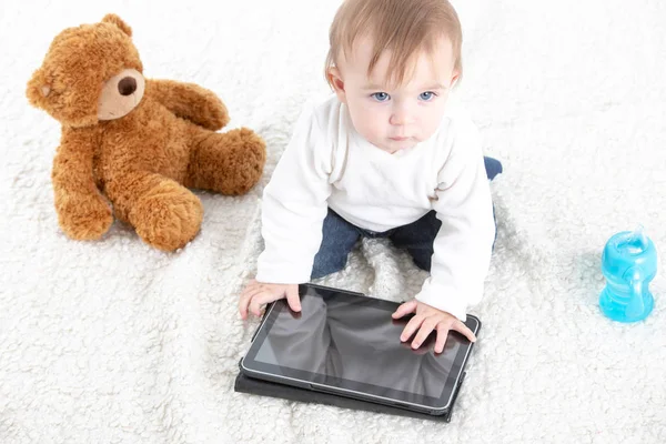 Little boy aanraken van een scherm van een tablet met een teddybeer op th — Stockfoto