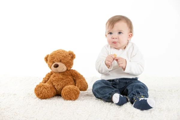 Baby eating with fingers with a teddy bear — Stock Photo, Image