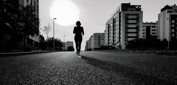 Black & white image of a woman who goes for a run on the empty street during the confinement of the Covid-19