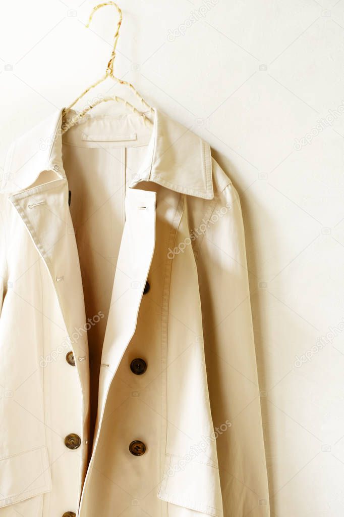 A beige or greige elegant trench coat isolated over white. opened in front. Close up