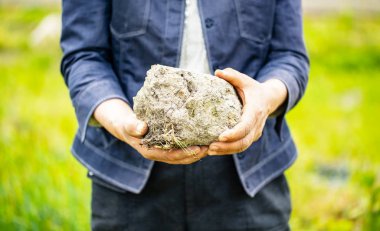Yaşlı kadın onun elinde büyük bir toprak tutar..