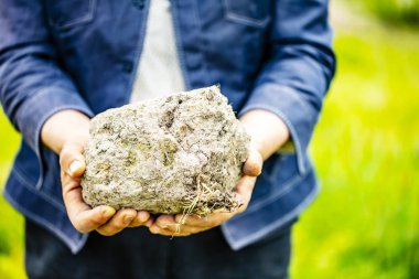 Yaşlı kadın onun elinde büyük bir toprak tutar..