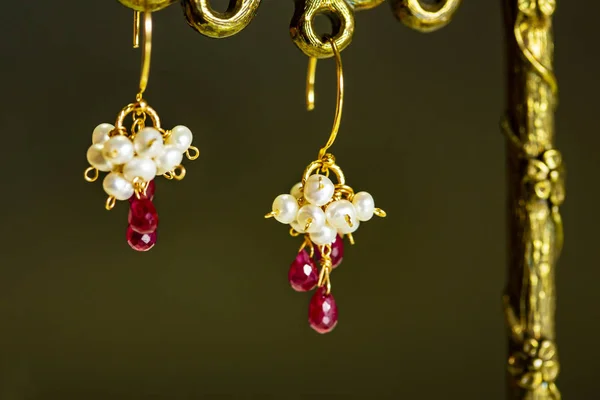 Zlaté náušnice s červenými rubíny s bílými perlami na černém pozadí. — Stock fotografie