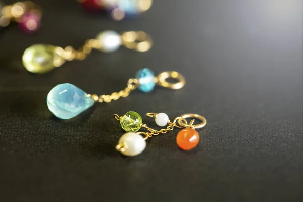 lemon quartz, ruby, pearl,labradorite,apatite, green chalcedony, blue topaz necklace charm isolated on black background.