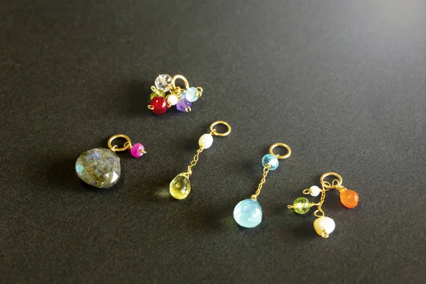 lemon quartz, ruby, pearl,labradorite,apatite, green chalcedony, blue topaz necklace charm isolated on black background.