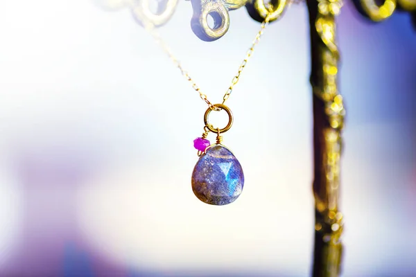 Colar dourado com com grande labradorite com pequeno rubi no fundo preto . — Fotografia de Stock