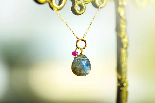 Colar dourado com com grande labradorite com pequeno rubi no fundo preto . — Fotografia de Stock