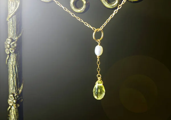 Złoty wisiorek z cytryny kwarcu lub kwarc żółty z białą perłą na czarnym tle. — Zdjęcie stockowe
