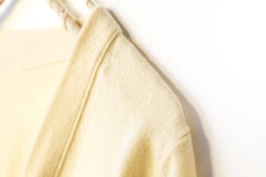 Beyaz giysili bir süveter beyaz arka planda asılı..