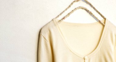 Beyaz elbiseli bir hırka beyaz arka planda asılı duruyor. Yaklaş..